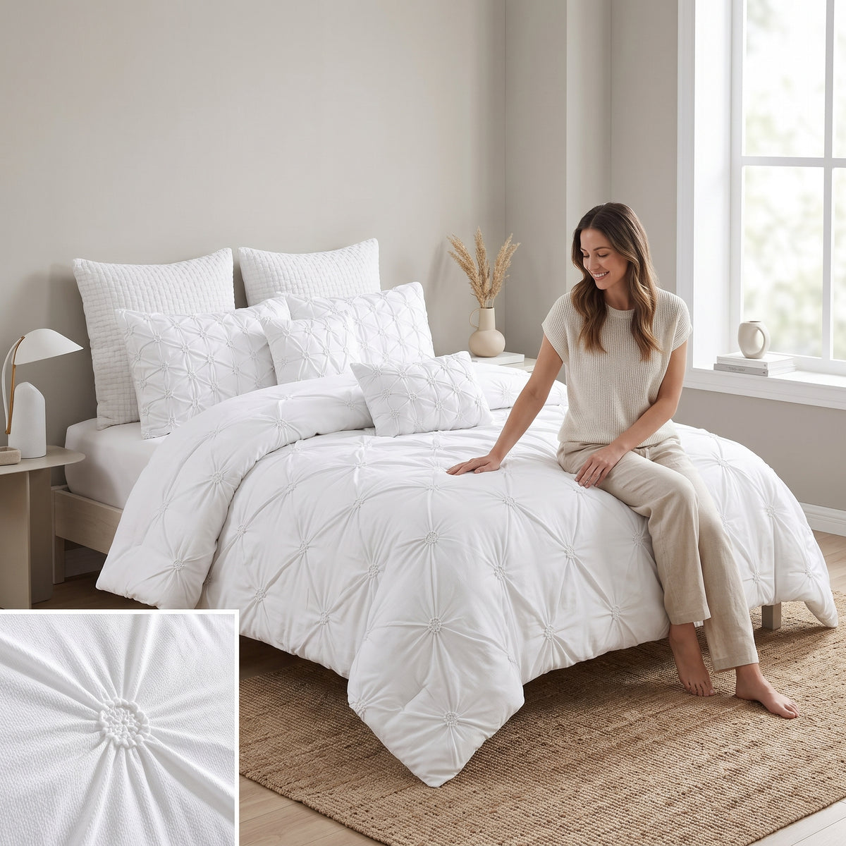 Ensemble de douillette Queen Chateau 7 pièces à plis pincés, blanc, avec une femme assise sur le lit et un gros plan des rosaces à plis pincés
