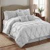 Chateau 7-piece queen pinch pleat comforter set in grey in a bedroom with a tufted grey headboard, angled view