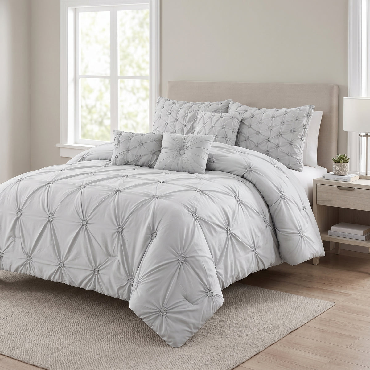 Chateau 7-piece queen pinch pleat comforter set in grey in a sunlit bedroom, side angle